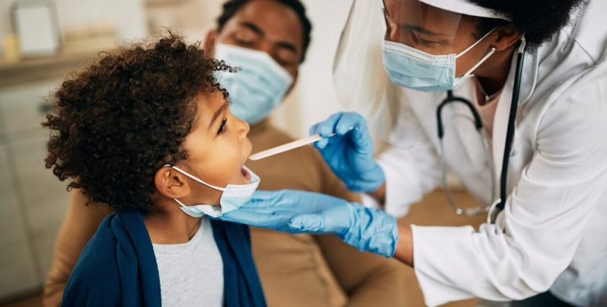 african-american-doctor-with-face-mask-examining-boy-s-throat-home-visit_637285-10515